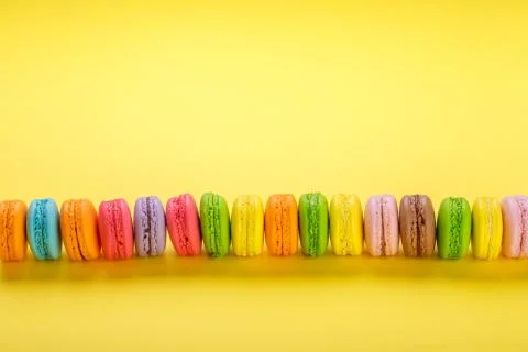 Colorful macaroons on yellow background. Macaroons are sweet meringue-based c Stock Photos