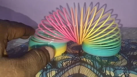 Colorful magic rainbow spring toy stretching dynamically with vibrant coils Stock Footage 334554740