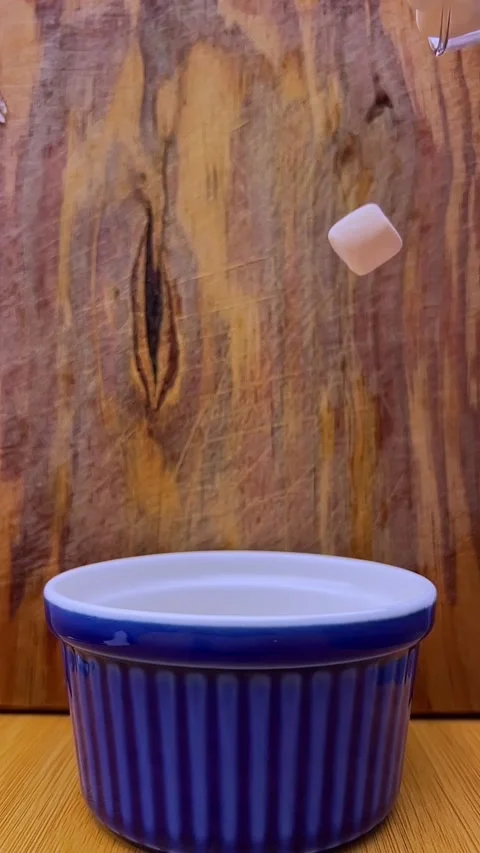 Colorful Marshmallows Falling into Blue Ceramic Cup on Wooden Table Stock Footage 343724904
