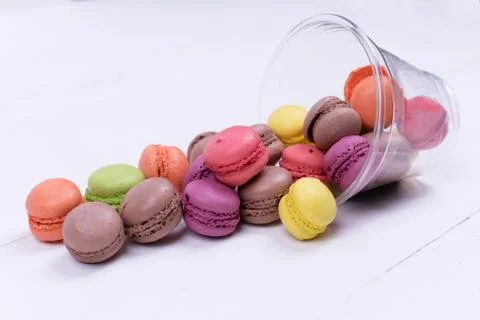 Colorful mini macarons a scattering of packaging on white background, sweet Stock Photos