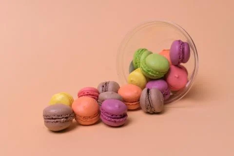 Colorful mini macarons a scattering of packaging on orange background, sweet Stock Photos