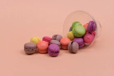 Colorful mini macarons a scattering of packaging on orange background, sweet Stock Photos