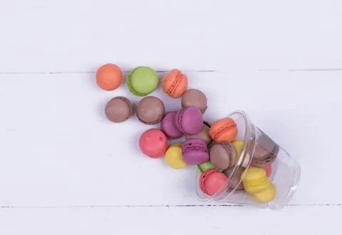 Colorful mini macarons a scattering of packaging on white background top view Stock Photos
