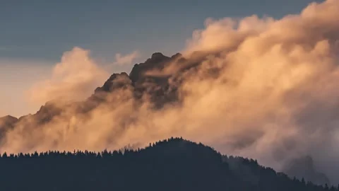 Colorful Misty clouds moving fast over alps mountains peak at sunset time lapse Stock Footage 299257979