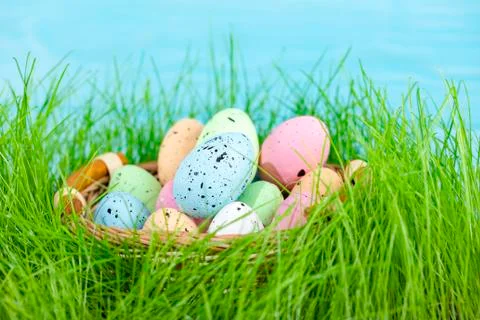 Colorful multi-colored Easter eggs lie on the green grass. Painted eggs in th Stock Photos