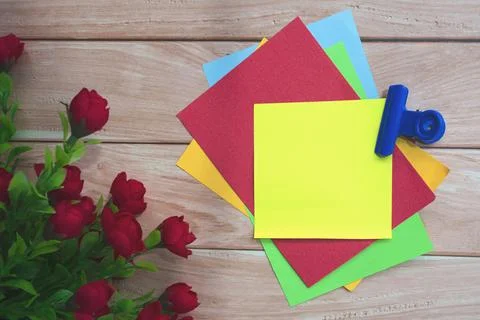 Colorful note flat lay with artificial flower on wooden background. Stock Photos