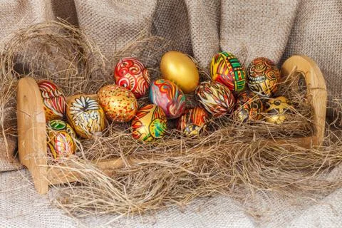 Colorful painted easter egg on hay in wooden shelf with sack background Foto stock
