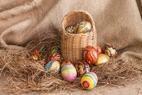 Colorful painted easter egg in wicker basket on hay Foto stock