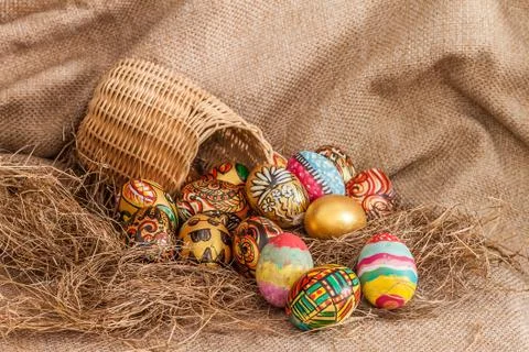 Colorful painted easter egg in wicker basket on hay Stock Photos