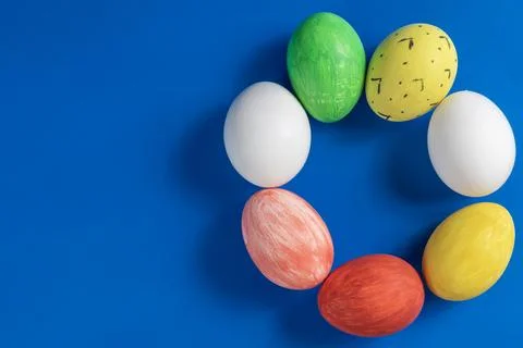 Colorful painted Easter eggs arranged in a circle on a blue background. 写真素材