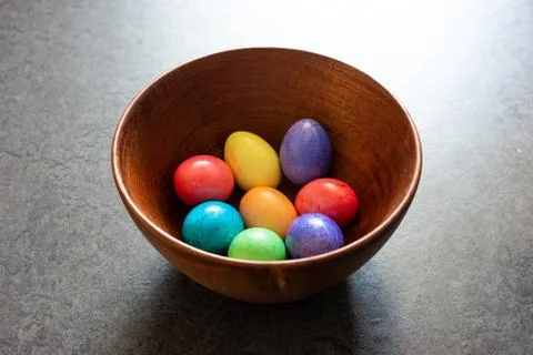 Colorful painted Easter Eggs in a brown wooden bowl shot in window daylight Fotos de archivo