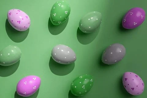 Colorful painted Easter eggs with dot patterns cast strong shadows on green Stock Photos