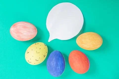 Colorful painted Easter eggs with a speech bubble on a green background. Stock Photos