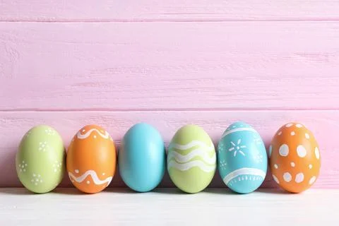 Colorful painted Easter eggs on table against wooden background, space for te 스톡 사진
