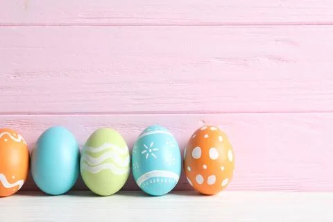 Colorful painted Easter eggs on table against wooden background, space for te Stock Photos