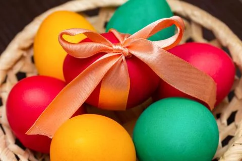 Colorful painted eggs with bow for Easter in a basket Stock Photos