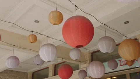 Colorful paper lanterns hanging from a ceiling outdoor during a festive celebrat 库存影片 343414533