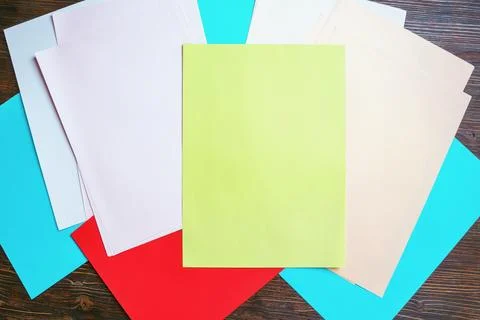 Colorful  paper sheets on dark rustic table, background. Copy space Stock Photos