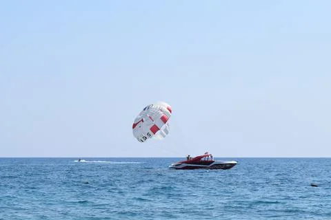 Colorful parasail wing flying over turquoise water. Parasailing, also known a Stock Photos