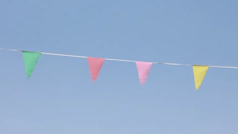 Colorful party pennants blowing in wind against clear blue sky Stock Footage 341878053