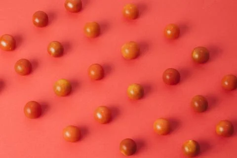 Colorful pattern of cherry tomatoes on red background. Top view Stock Photos