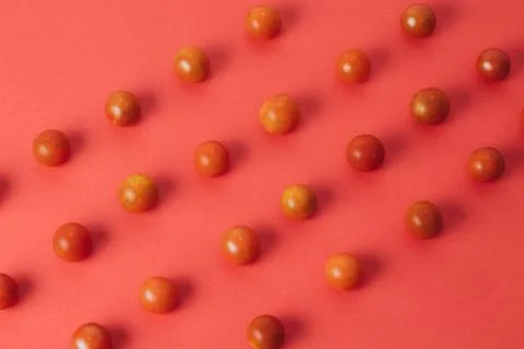 Colorful pattern of cherry tomatoes on red background. Top view Stock Photos
