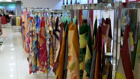 Colorful, pattern-printed silk scarves hang displayed on clothing racks inside Stock Footage 341553719
