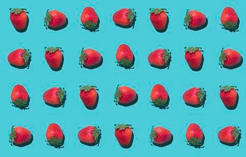 Colorful pattern of strawberries spinning on a cyan background. Top view Stock Photos