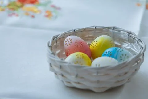 Colorful Patterned Easter Eggs in White Wicker Basket on White Tablecloth B.. Stock Photos