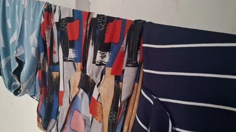 Colorful patterned laundry drying on indoor rack Stock Footage 345362124