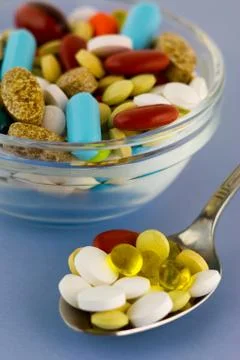 Colorful pills in bowl and spoon Stock Photos