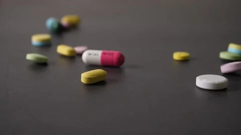 Colorful pills falling on a table in slow motion Stock Footage 160544257