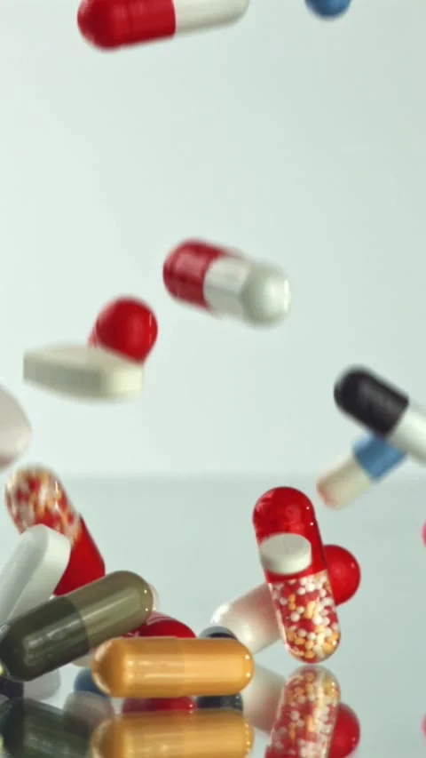 Colorful pills falling on white studio slow motion Filmed on a high-speed camera Stock Footage 335396840