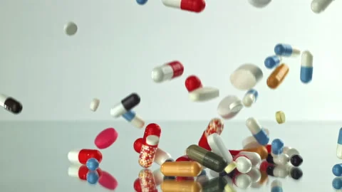Colorful pills falling on white studio slow motion Filmed on a high-speed camera Stock Footage 335423947