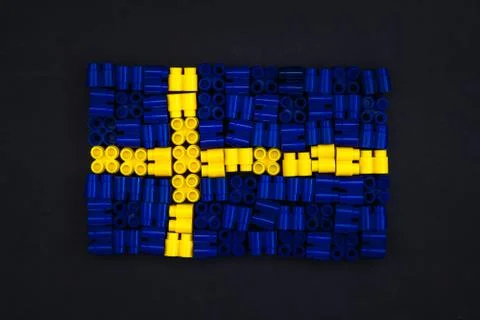 Colorful plastic bricks which form the Sweden flag on black paper background. Foto stock