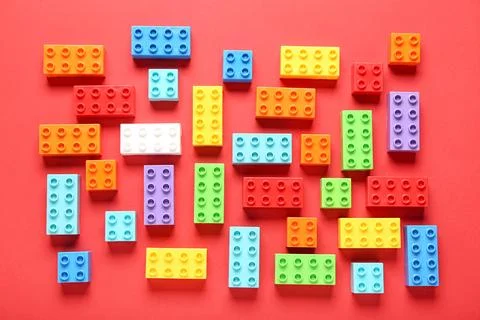 Colorful plastic building blocks on red background Stock Photos
