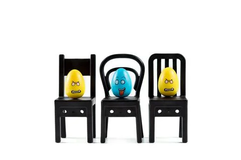 Colorful Plastic Easter Eggs on small chairs on white background Foto stock