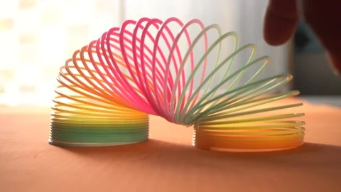 Colorful plastic rainbow magic spring toys, commonly known as slinkies Stock Footage 335875038