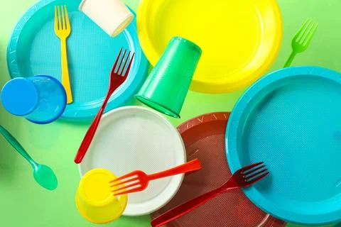 Colorful plastic tableware levitating on green background Stock Photos