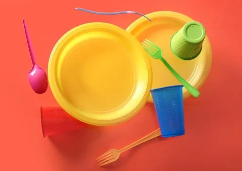 Colorful plastic tableware levitating on red background Stock Photos
