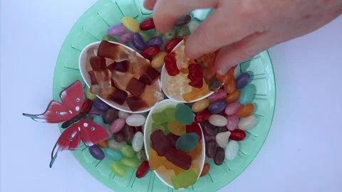 Colorful plate full of assorted candies with a hand picking sweets, isolated on Stock Footage 331850677