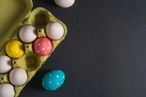 Colorful polka dot Easter eggs in egg tray on dark grey black plain background Stock Photos