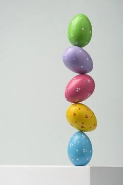 Colorful polka dot Easter eggs form vertical stack on white pedestal, minim.. 写真素材