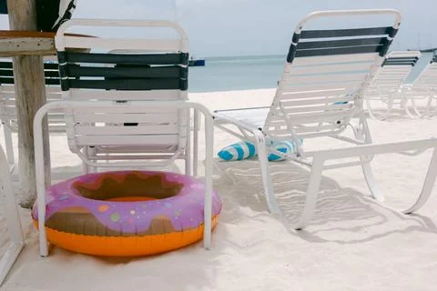 Colorful pool float rests beside lounge chairs at a beach on a sunny day in a Stock-Fotos