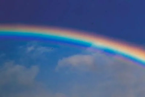 Colorful rainbow with dramatic storm sky above and serene sky below Stock Illustration