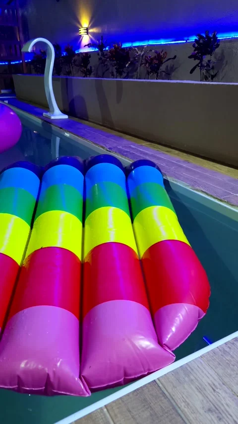 Colorful rainbow inflatable float in a modern pool with blue lights. Stock Footage 312898165