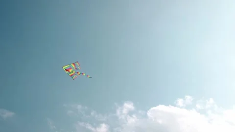 A colorful rainbow kite flying high in the blue sky on a sunny day. Stock Footage 316617171