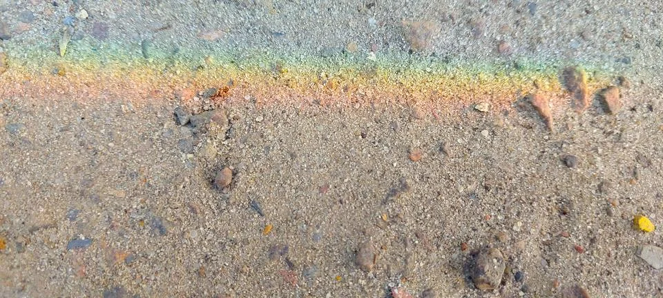 Colorful Rainbow Pattern Formed on the Sandy Surface Under Bright Sunlight Stock Photos