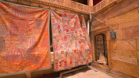 Colorful Rajasthani patchwork tapestry hanging on sandstone wall in Jaisalmer Stock Footage 346113887