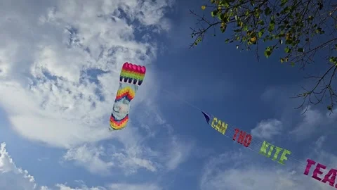 A colorful, rectangular kite soars gracefully against a bright blue sky clouds. Stock Footage 302772477